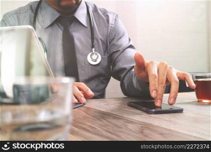smart medical doctor hand working with smart phone,digital tablet computer,stethoscope eyeglass,on wood desk,filter effect