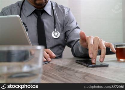 smart medical doctor hand working with smart phone,digital tablet computer,stethoscope eyeglass,on wood desk