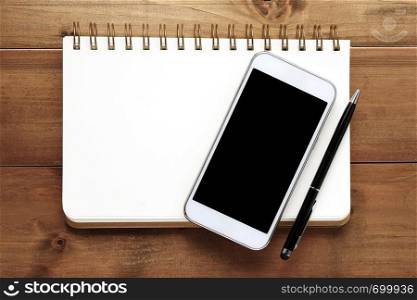 Smart phone and blank note book on wood background, business and technology concept, mock up