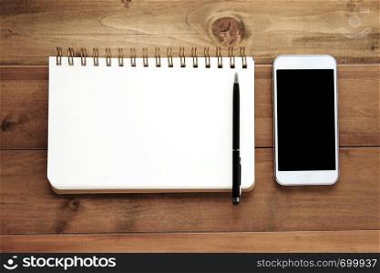 Smart phone and blank note book on wood background, business and technology concept, mock up