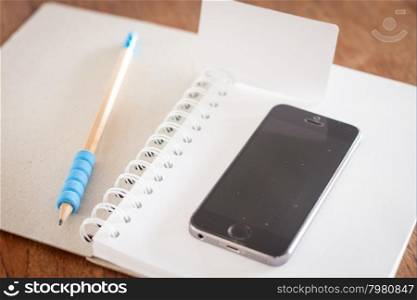 Smart phone and business card on opened notebook, stock photo