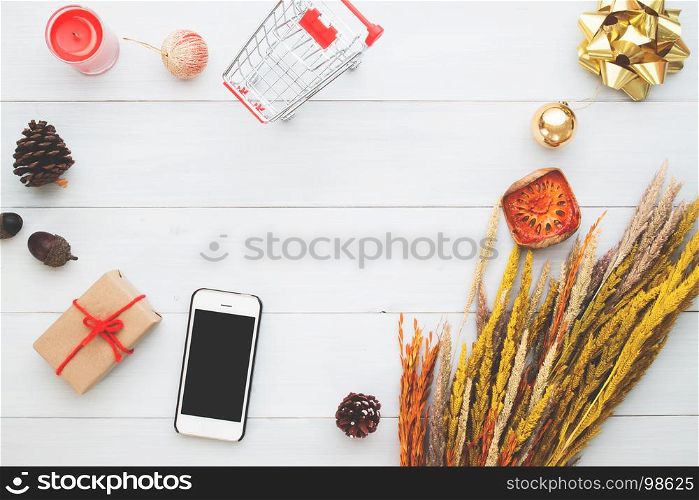 Smart phone and Christmas ornament decoration on white wooden background, Mock up for shopping concept