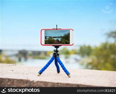 smart phone stands on a tripod and takes a panorama of nature