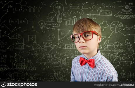 Smart schoolboy. Genius boy in red glasses near blackboard with formulas