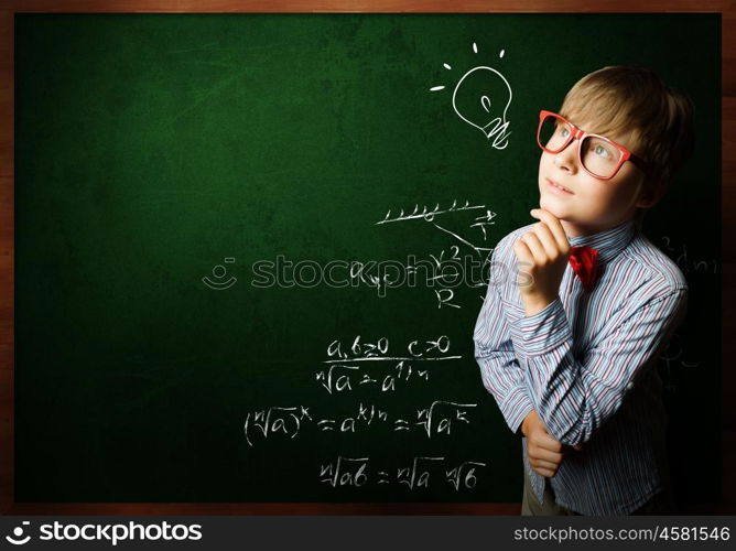 Smart schoolboy. Genius boy in red glasses near blackboard with formulas