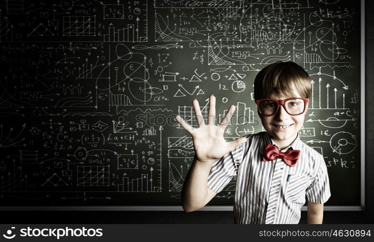 Smart schoolboy. Genius boy in red glasses near blackboard with formulas