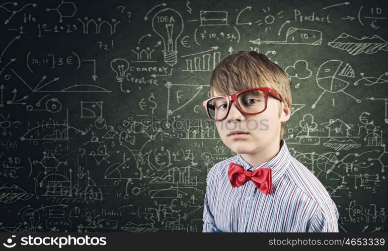 Smart schoolboy. Genius boy in red glasses near blackboard with formulas