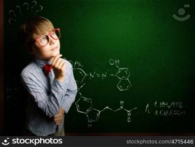 Smart schoolboy. Genius boy in red glasses near blackboard with formulas