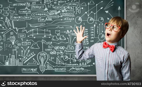 Smart schoolboy. Genius boy in red glasses near blackboard with formulas