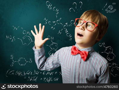 Smart schoolboy. Genius boy in red glasses near blackboard with formulas