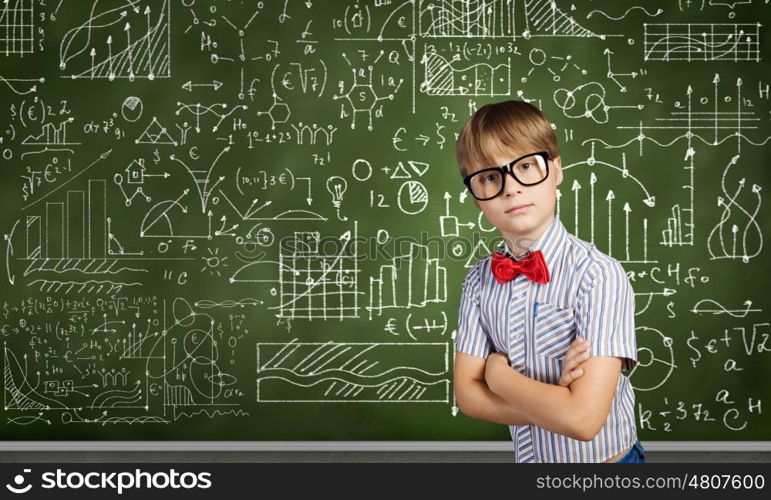 Smart schoolboy. Genius boy in red glasses near blackboard with formulas