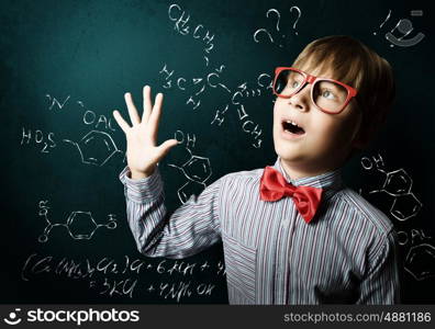 Smart schoolboy. Genius boy in red glasses near blackboard with formulas