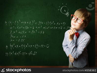 Smart schoolboy. Smart boy in red glasses near blackboard with formulas