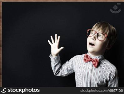 Smart schoolboy. Smart boy in red glasses near blackboard with formulas