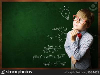 Smart schoolboy. Smart boy in red glasses near blackboard with formulas