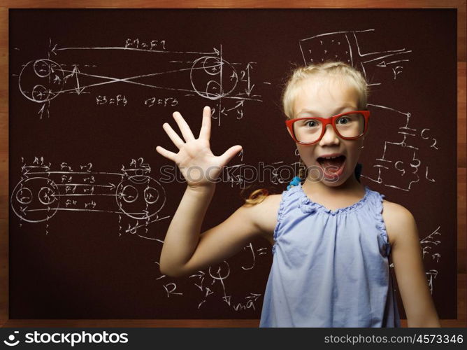 Smart schoolgirl. Genius girl in red glasses near blackboard with formulas