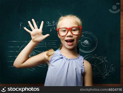 Smart schoolgirl. Genius girl in red glasses near blackboard with formulas