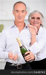 Smart senior couple with bottle of champagne