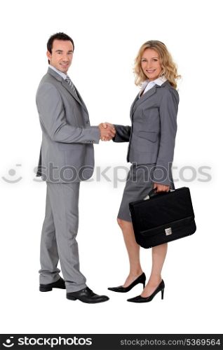 Smart suited man and woman shaking hands