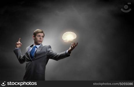 Smart thinking. Young thoughtful businessman and human brain above his head
