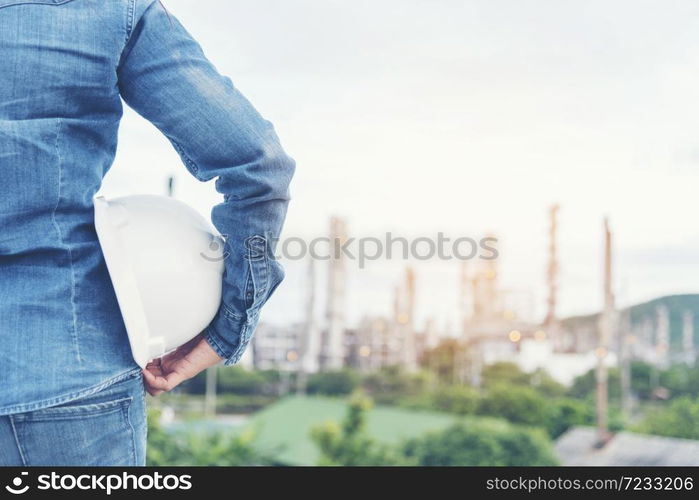 Smart woman engineer holding white hard hat on hand and look at refinery industry plant at industry factory center area. Engineering Concept