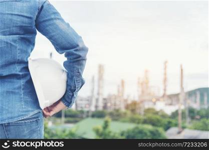 Smart woman engineer holding white hard hat on hand and look at refinery industry plant at industry factory center area. Engineering Concept