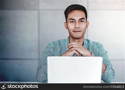Smart Young Asian Businessman Working on Computer Laptop in Office. Smiling and looking at Camera