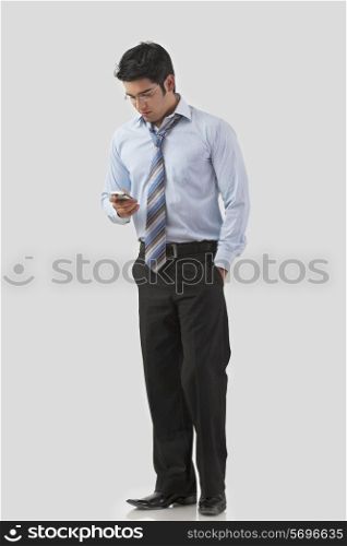 Smart young businessman texting over colored background