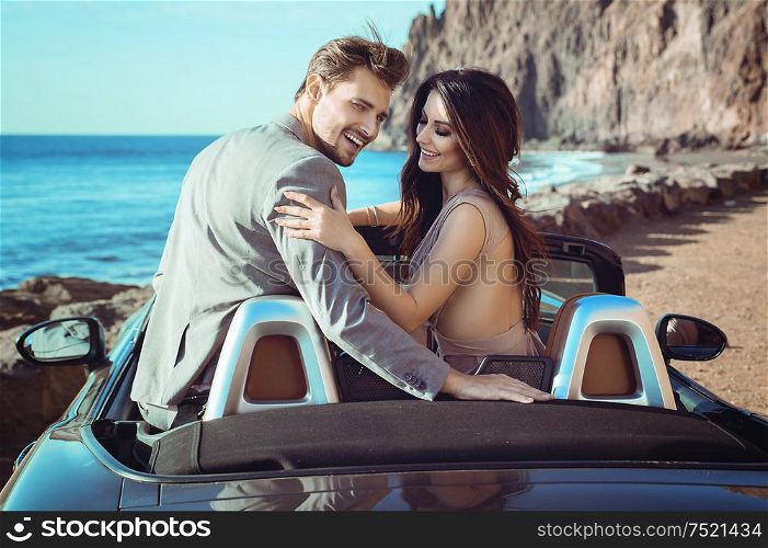 Smart, young couple riding a luxurious convertible