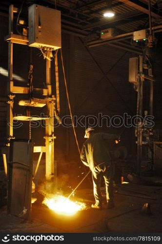 SmartLite Foundry en Product bezoek OMCO. A man working in a cast iron factory close to the melting pit of the foundry