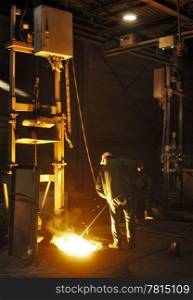SmartLite Foundry en Product bezoek OMCO. A man working in a cast iron factory close to the melting pit of the foundry