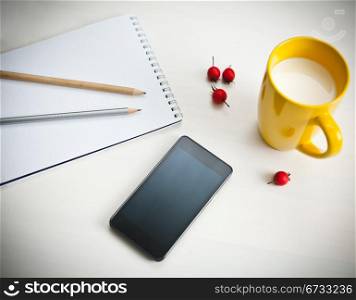 Smartphone, cup of milk and notebook