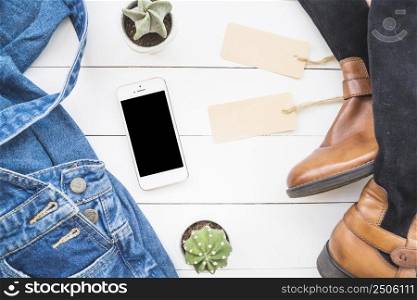 smartphone near jean cloth high boots with tags cactus