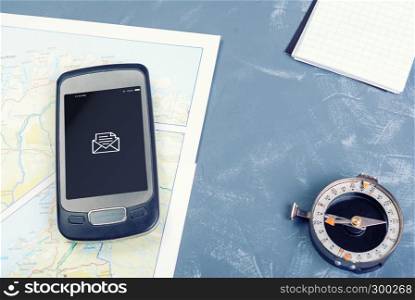Smartphone, pad, compass on a dark background. Smartphone on a tourist map, compass and notepad