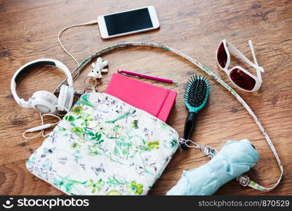 Smartphone sunglasses headphones and other things pulled out of handbag put on a table