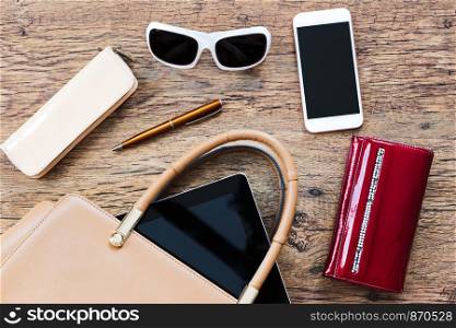 Smartphone sunglasses wallet and other things pulled out of handbag put on a table
