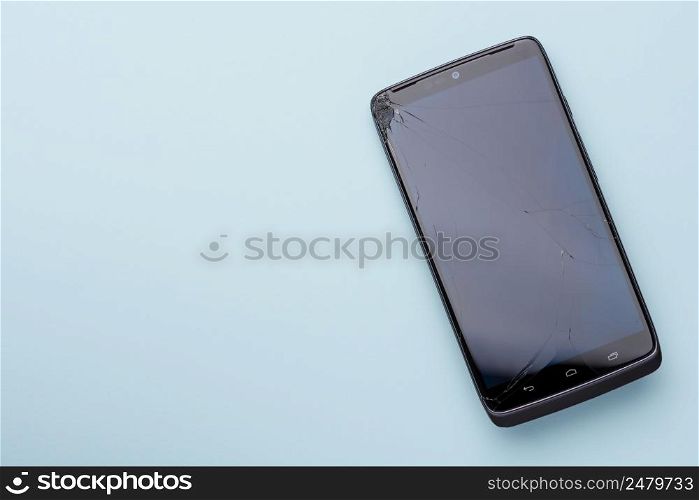 Smartphone with broken glass screen phone touch screen on blue background with copy space.