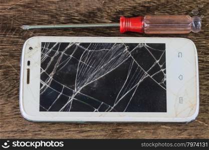 smartphone with broken screen on wooden background