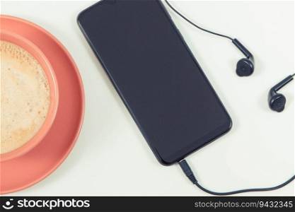 Smartphone with connected headphones and cup of coffee with milk. Relaxation time with music. White background. Smartphone with connected headphones and coffee with milk. Relaxation time with music. White background