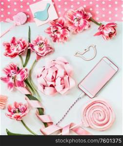 Smartphone with pink flowers and ribbon on white desk. Top view. Mothers day. Birthday. Blank screen . Greeting and technology. Copy space