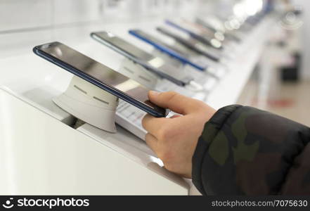 Smartphones on shelf in the store. Concept for communications and technology. Boy buying mobile phone in technology shop.