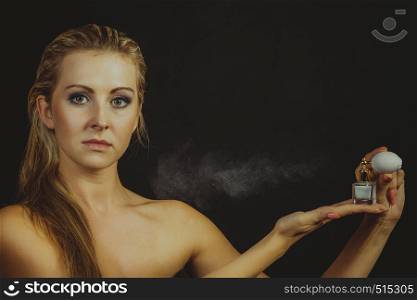Smell, elegance concept. Beautiful elegant blonde woman with necklace applying perfume after shower on naked body, studio shot on dark background, sepia.. Beautiful woman with holding and applying perfume