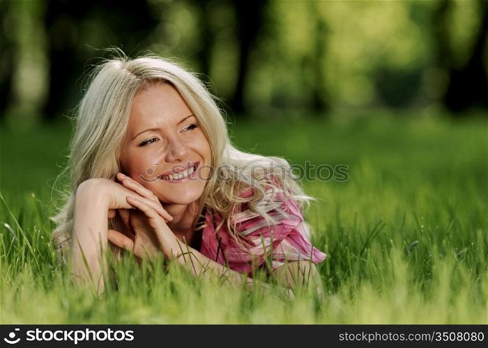 smile blonde lying on green grass