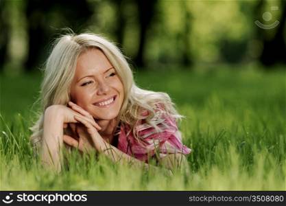 smile blonde lying on green grass