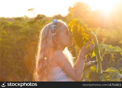 smile little girl with sunflower at the sunset time