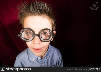 Smiled child with big glasses. Red curtain background