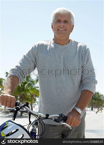 Smiled senior man on bicycle on tropical beach