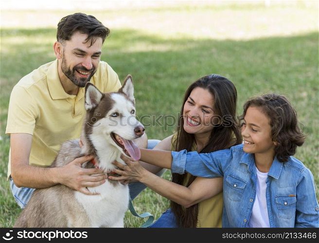 smiley boy parents petting dog while park