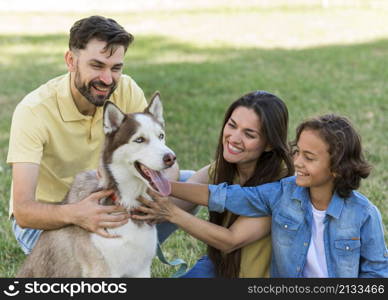 smiley boy parents petting dog while park