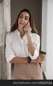 smiley businesswoman talking phone while having coffee